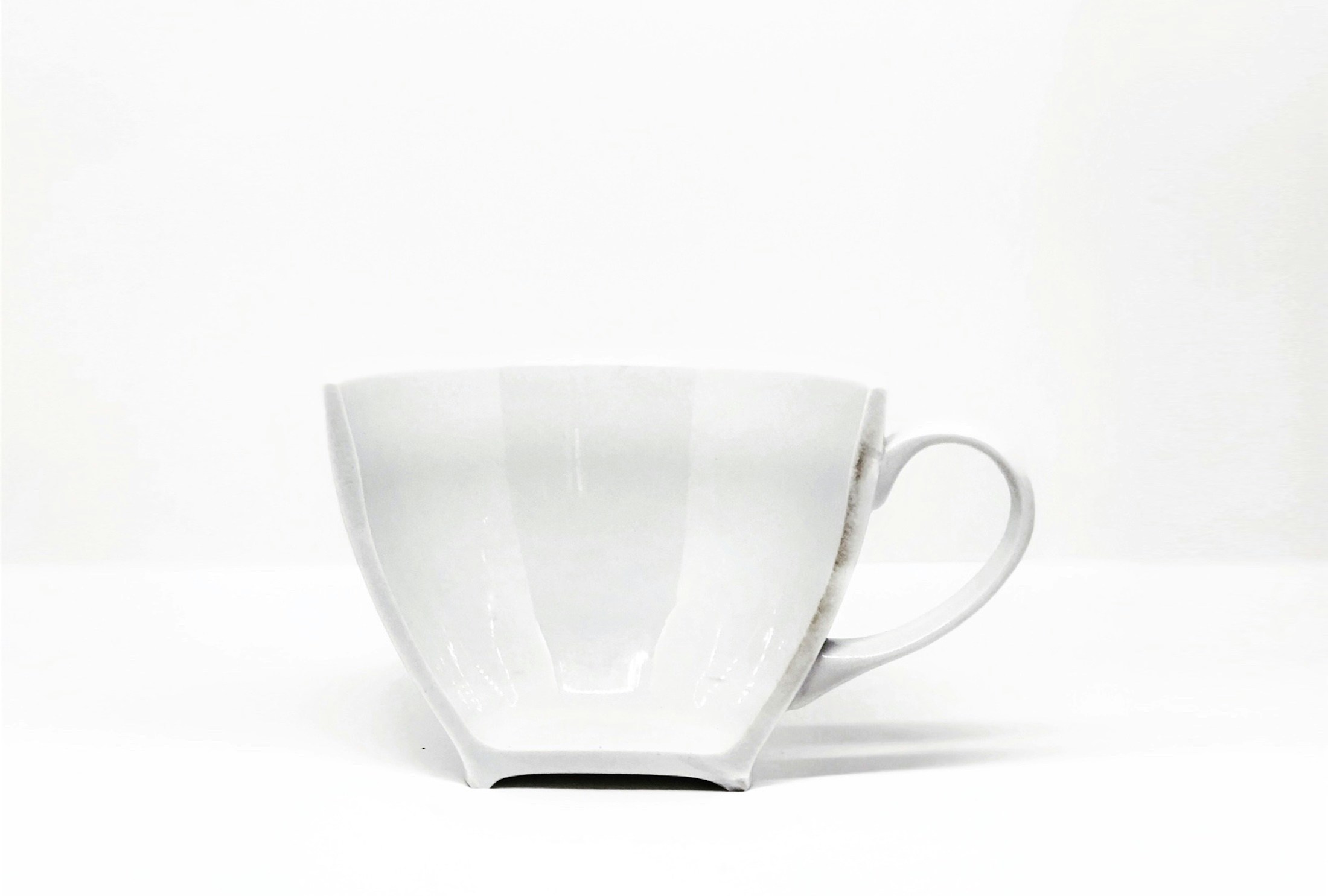 a cup is white and has two small curved cups