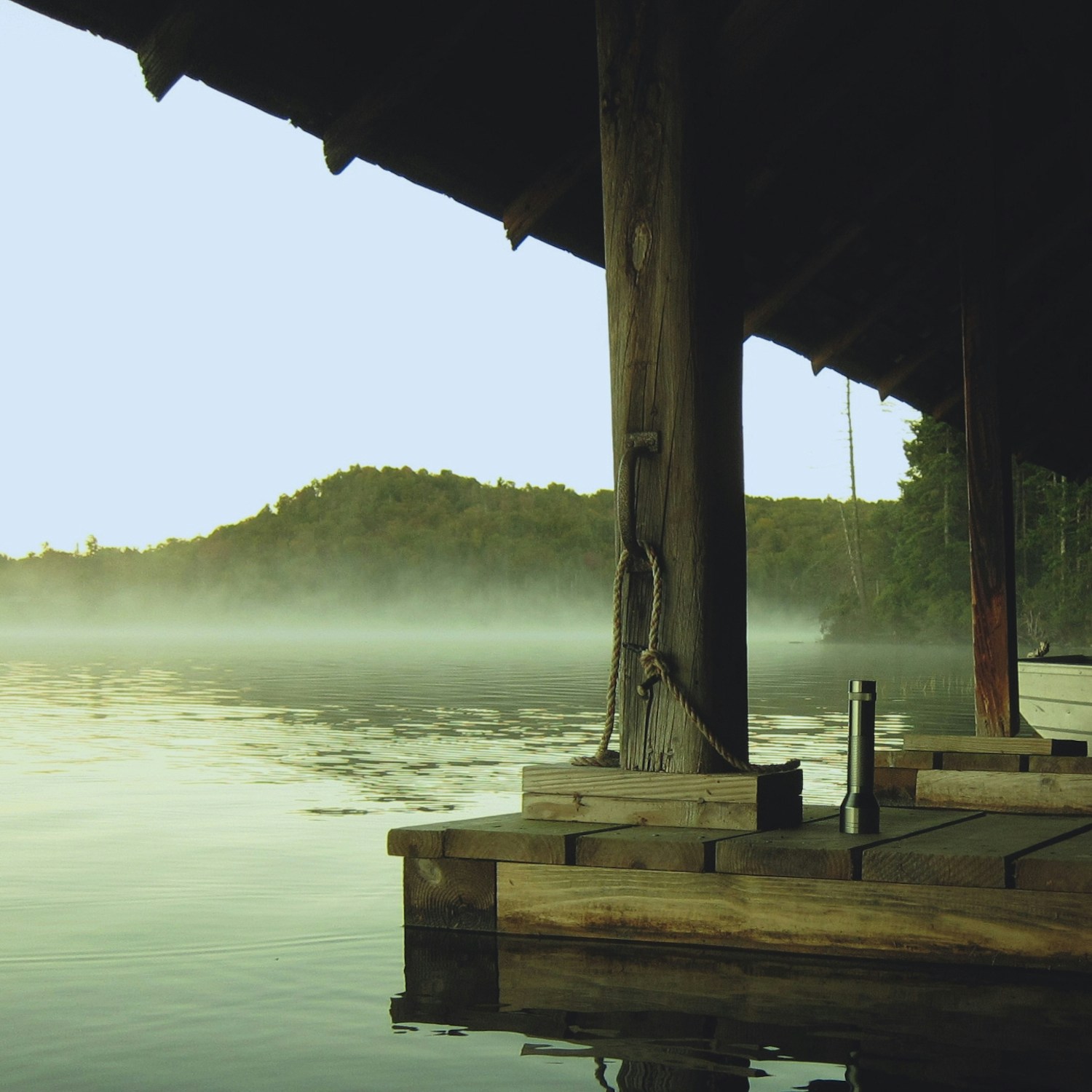 fog surrounds the dock on a lake during the day