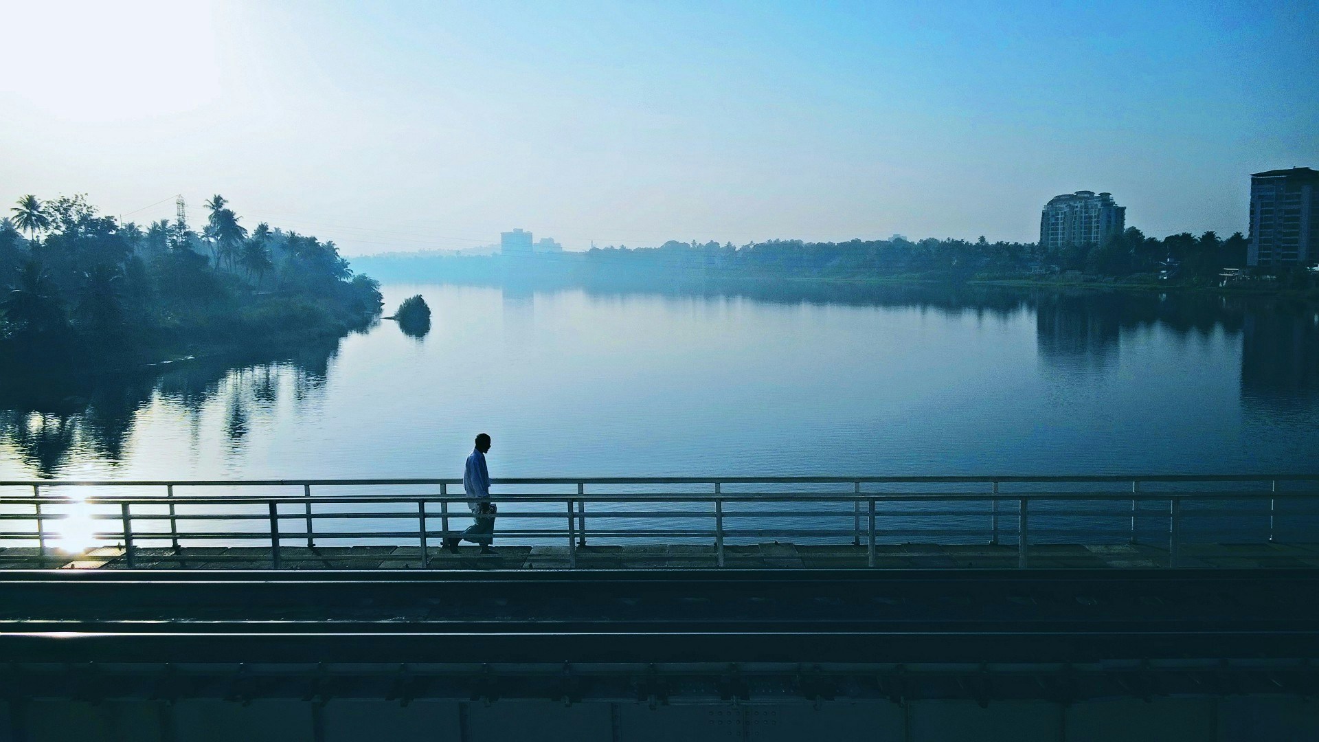a man is walking over a bridge overlooking the water