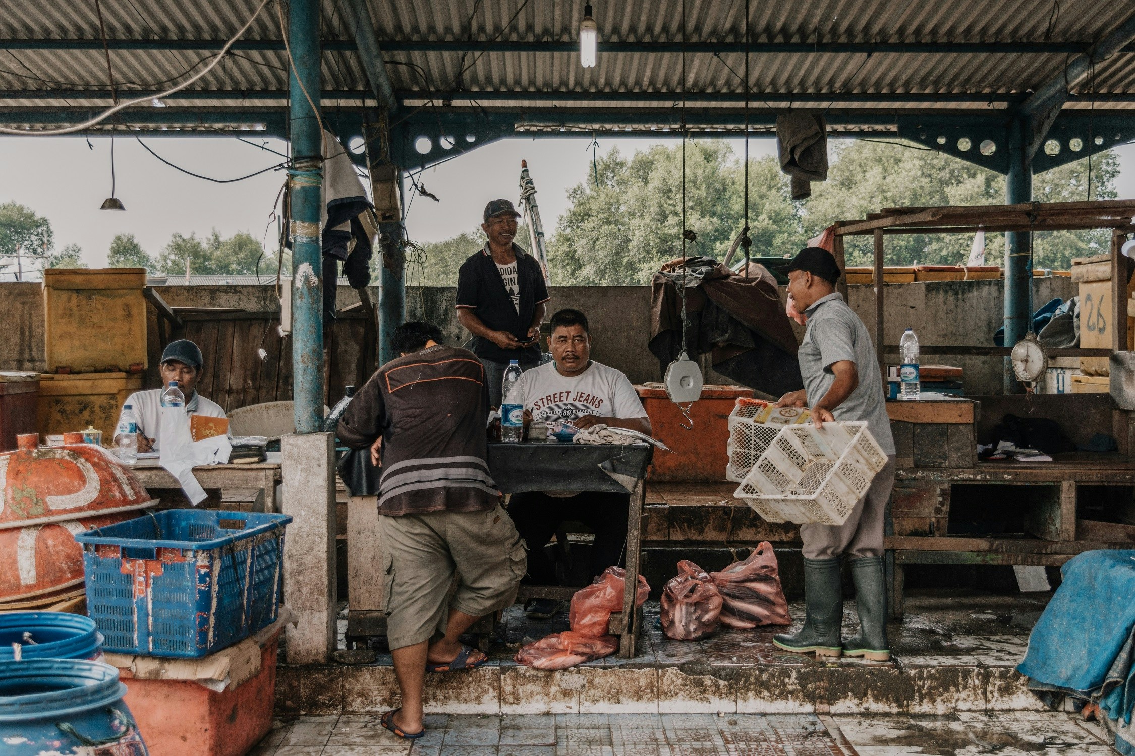 four men standing in a market with bags and food