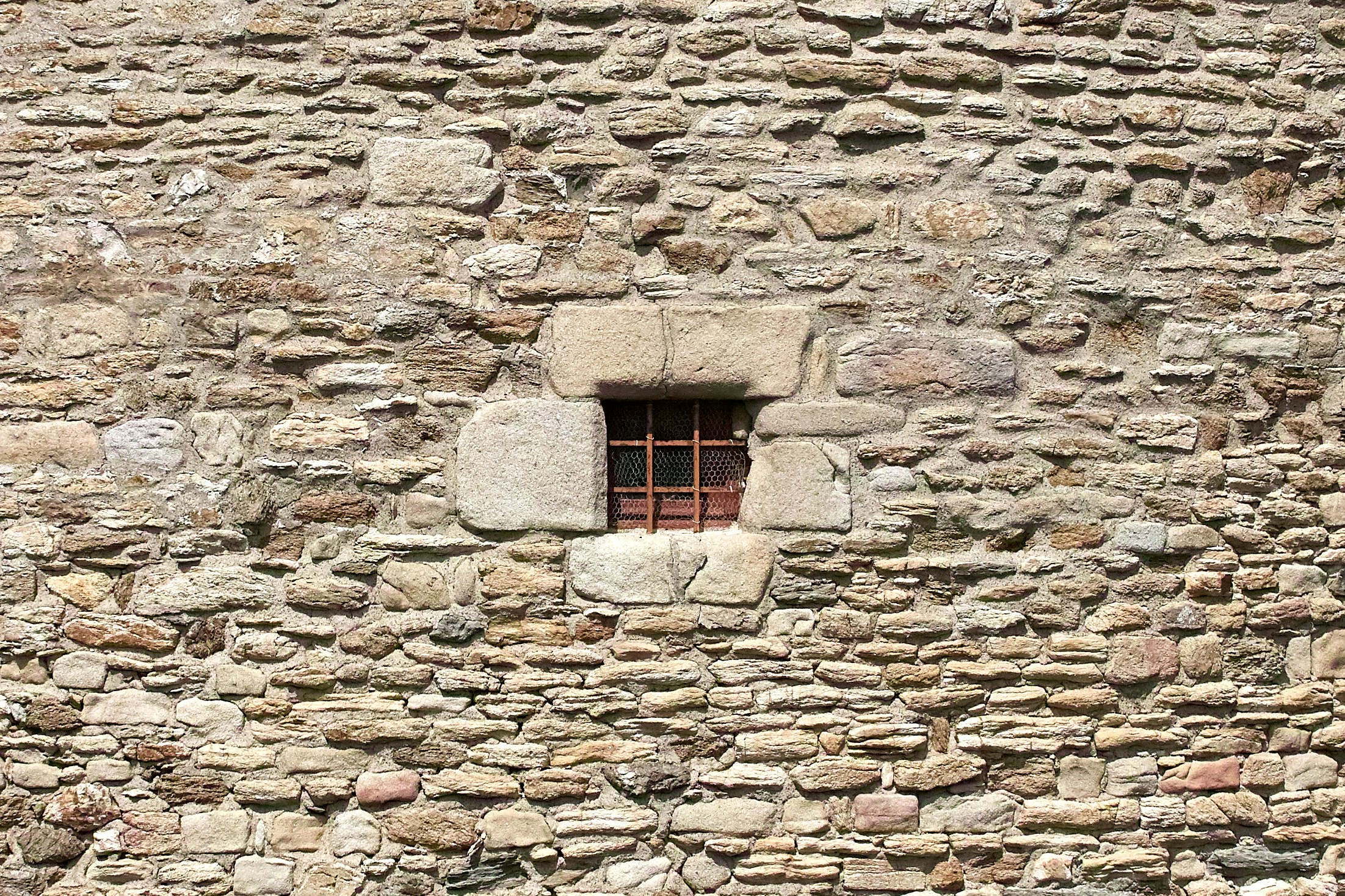 the side of an old stone building with a small window in it