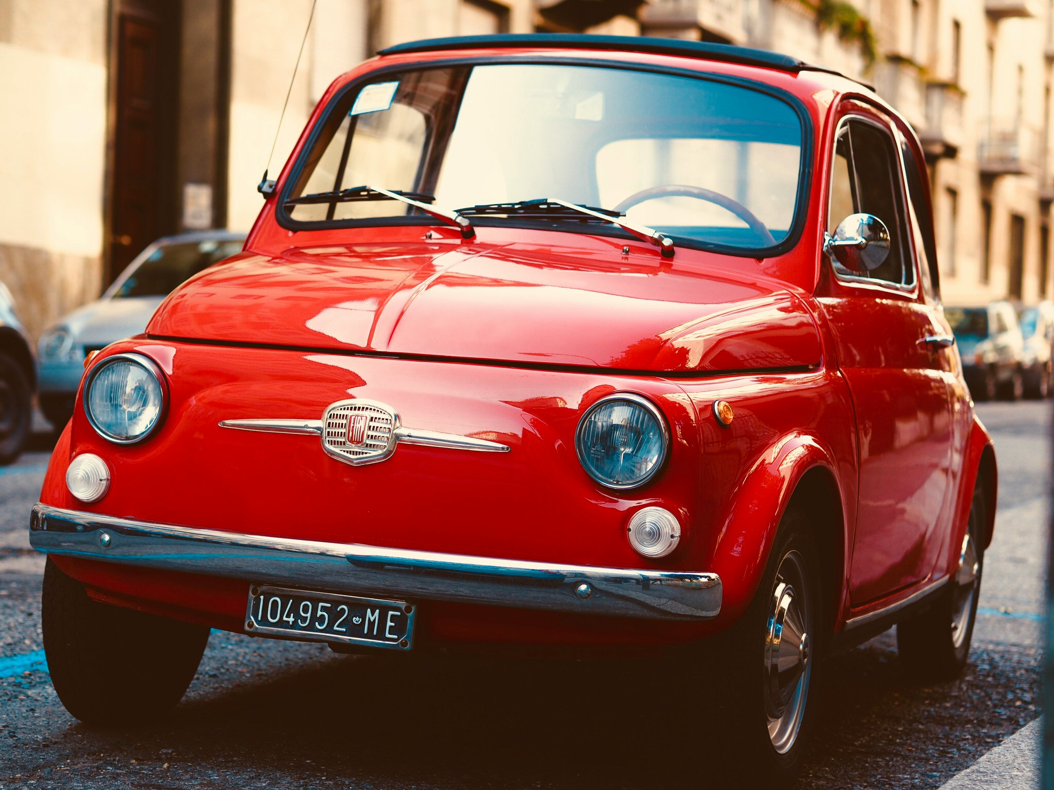 an old car sits parked on the street