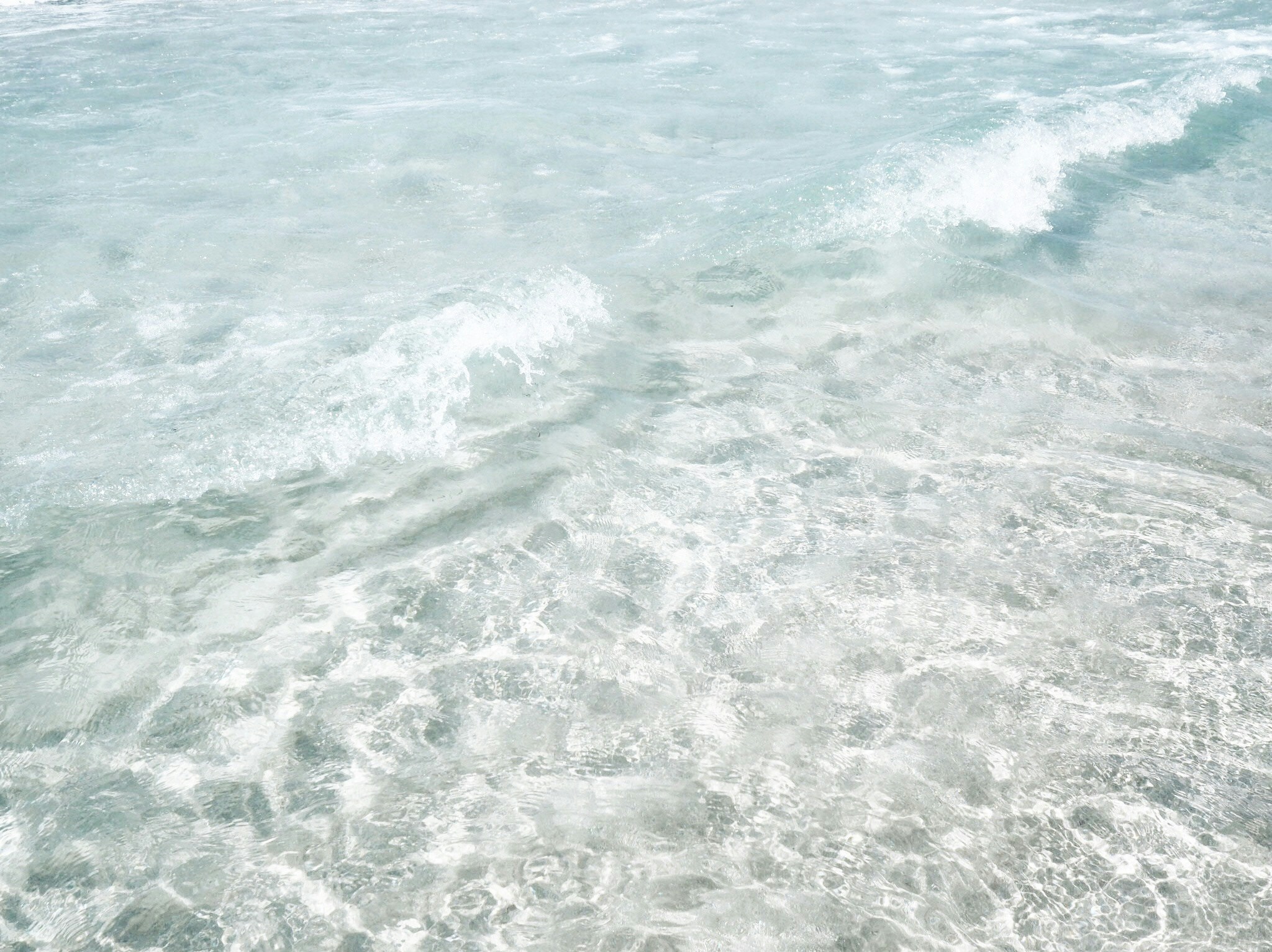 the sea is covered in thin waves and soft sand