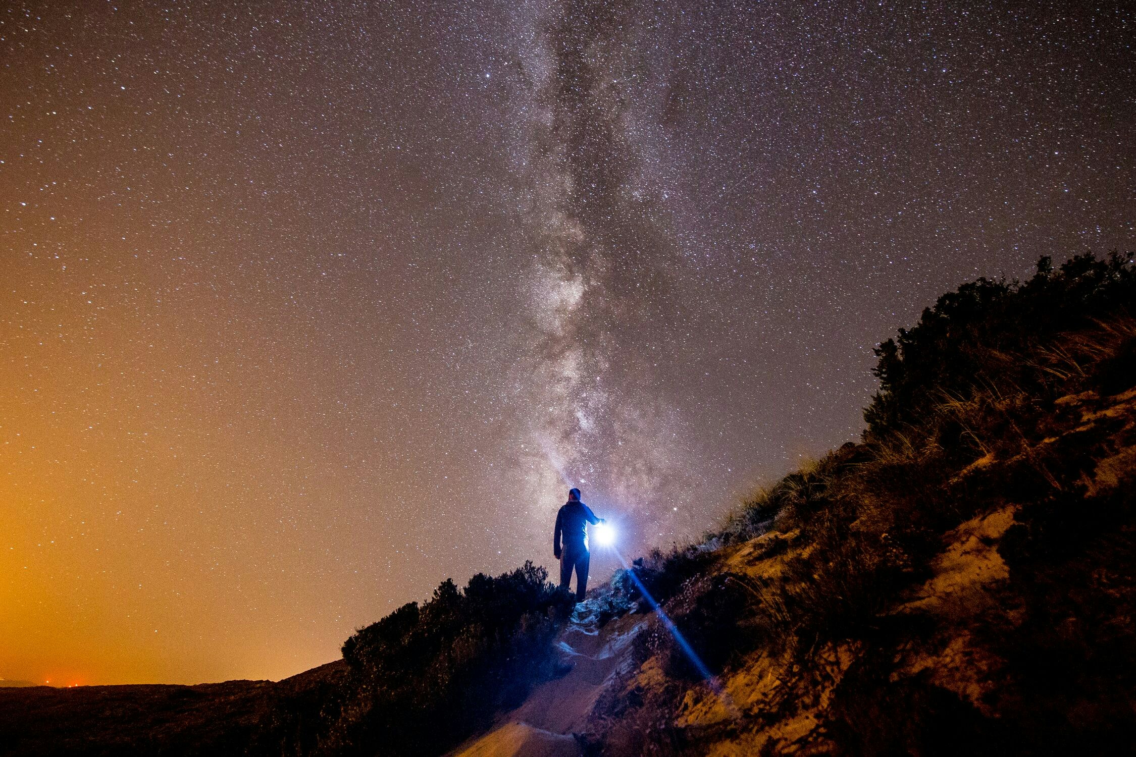 a person standing on a trail below the stars