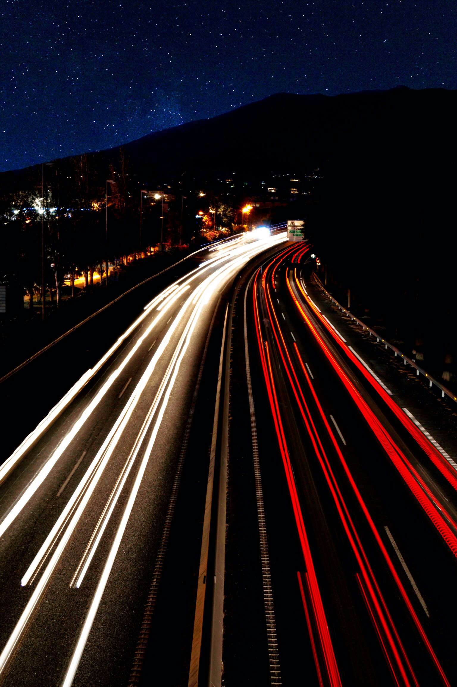 an elevated view of a road with headlights at night