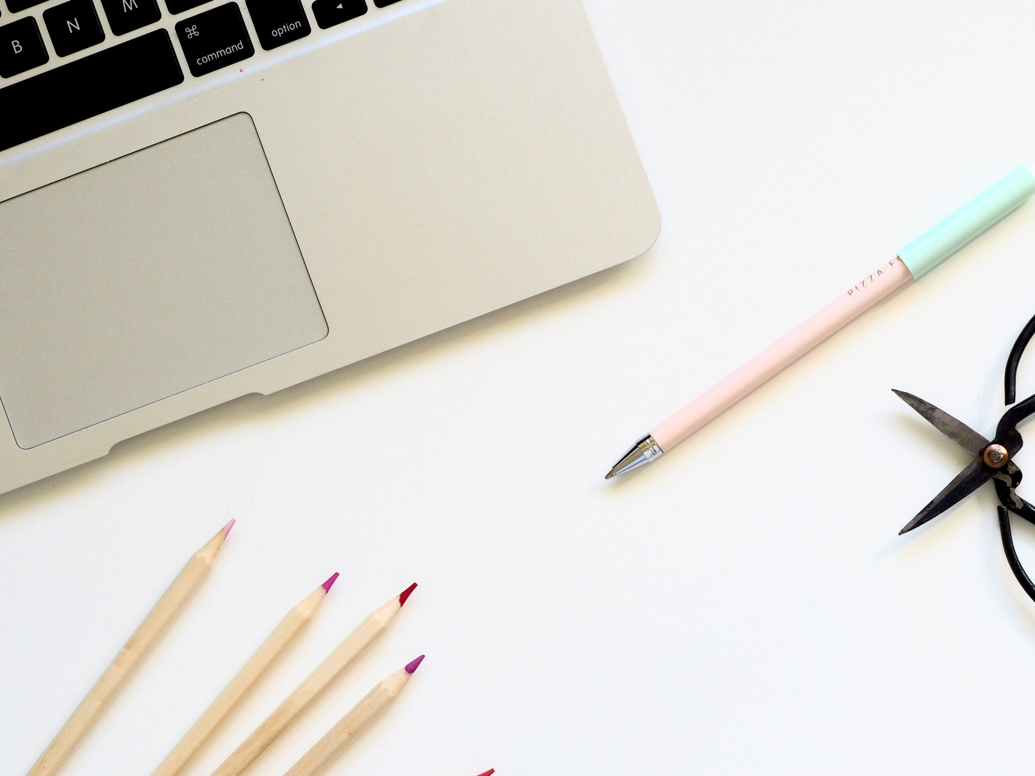 a pair of scissors and a pencil laying on top of an open laptop