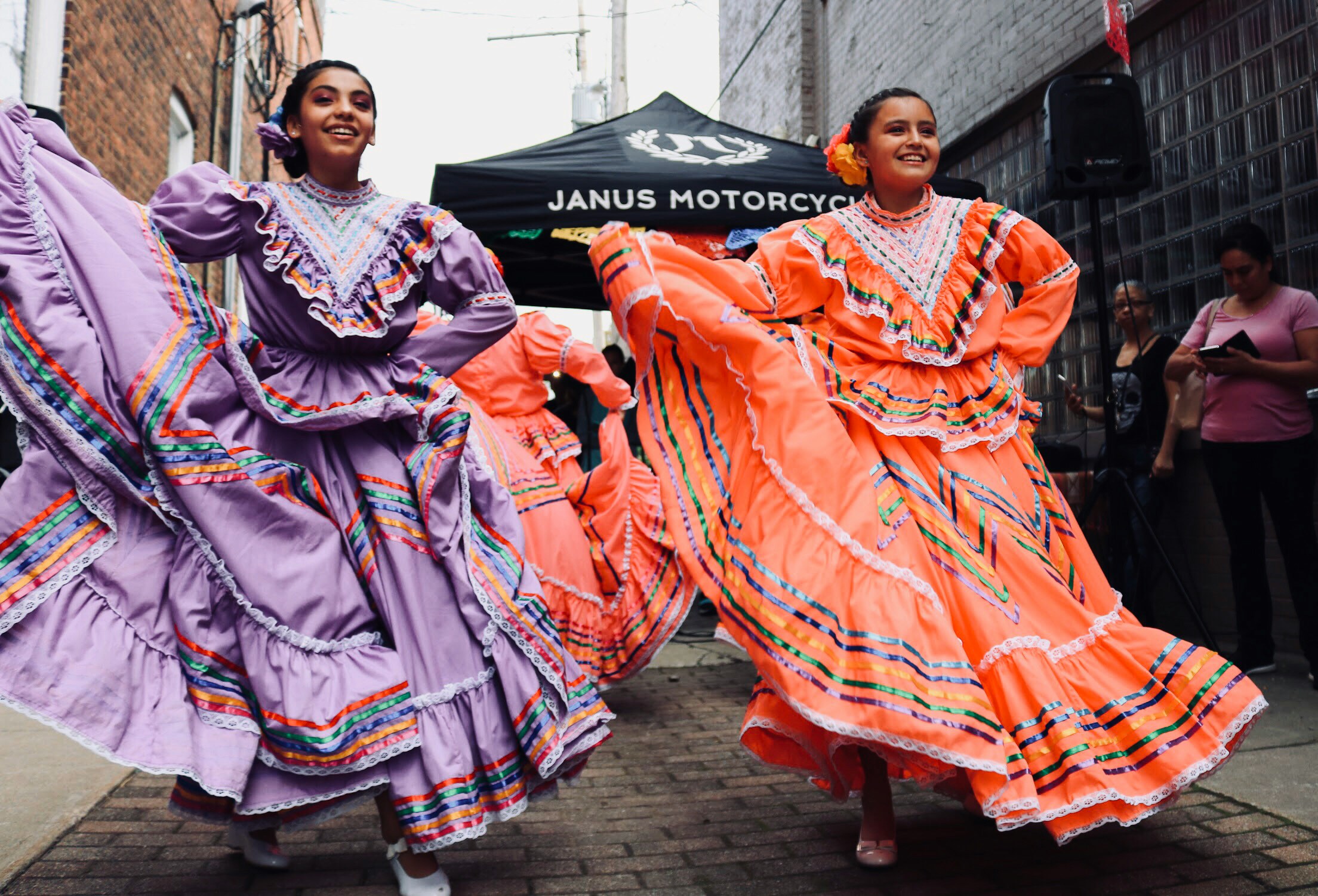 two women in colorful dresses dancing on the street