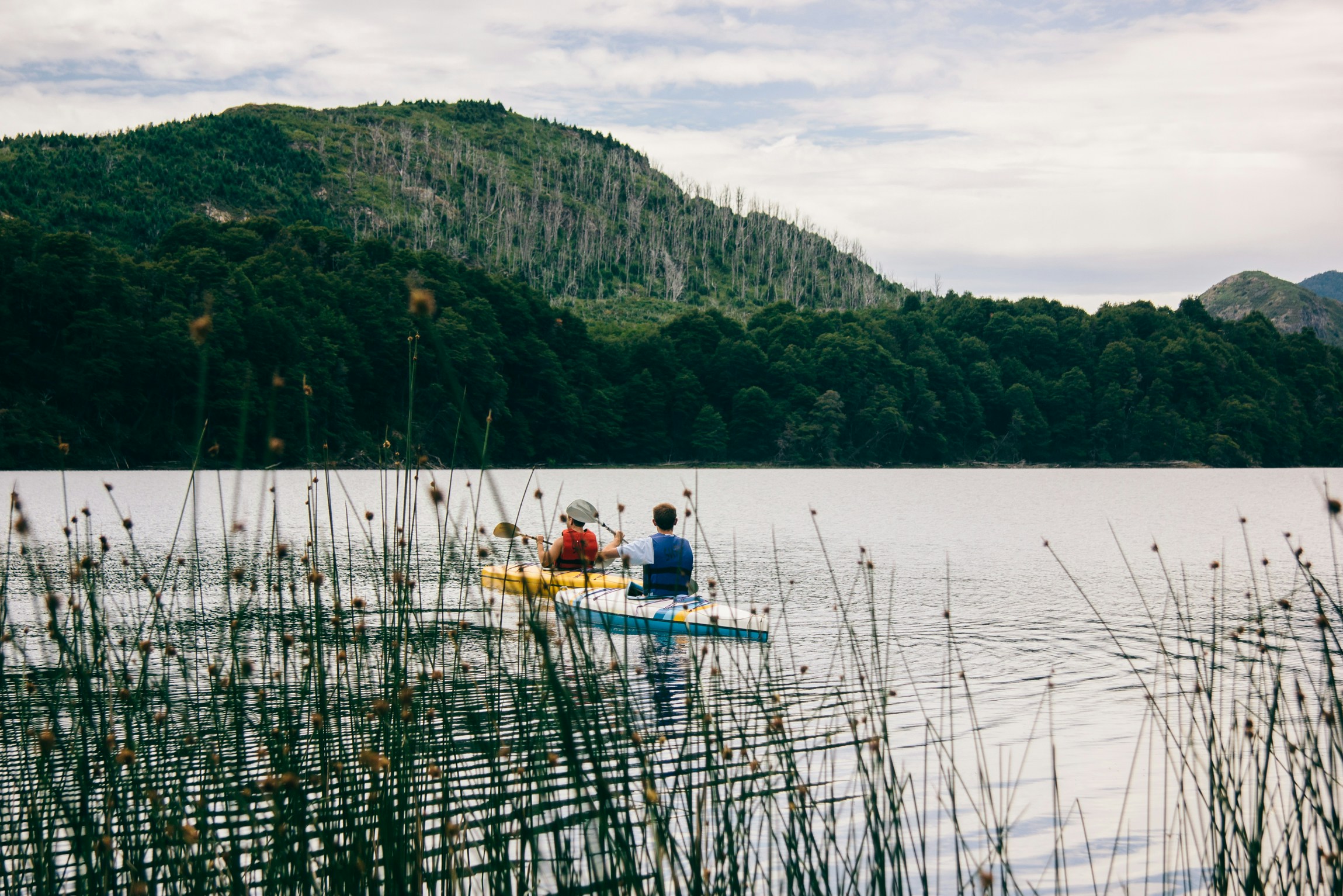 two people paddling in a yellow boat on a lake