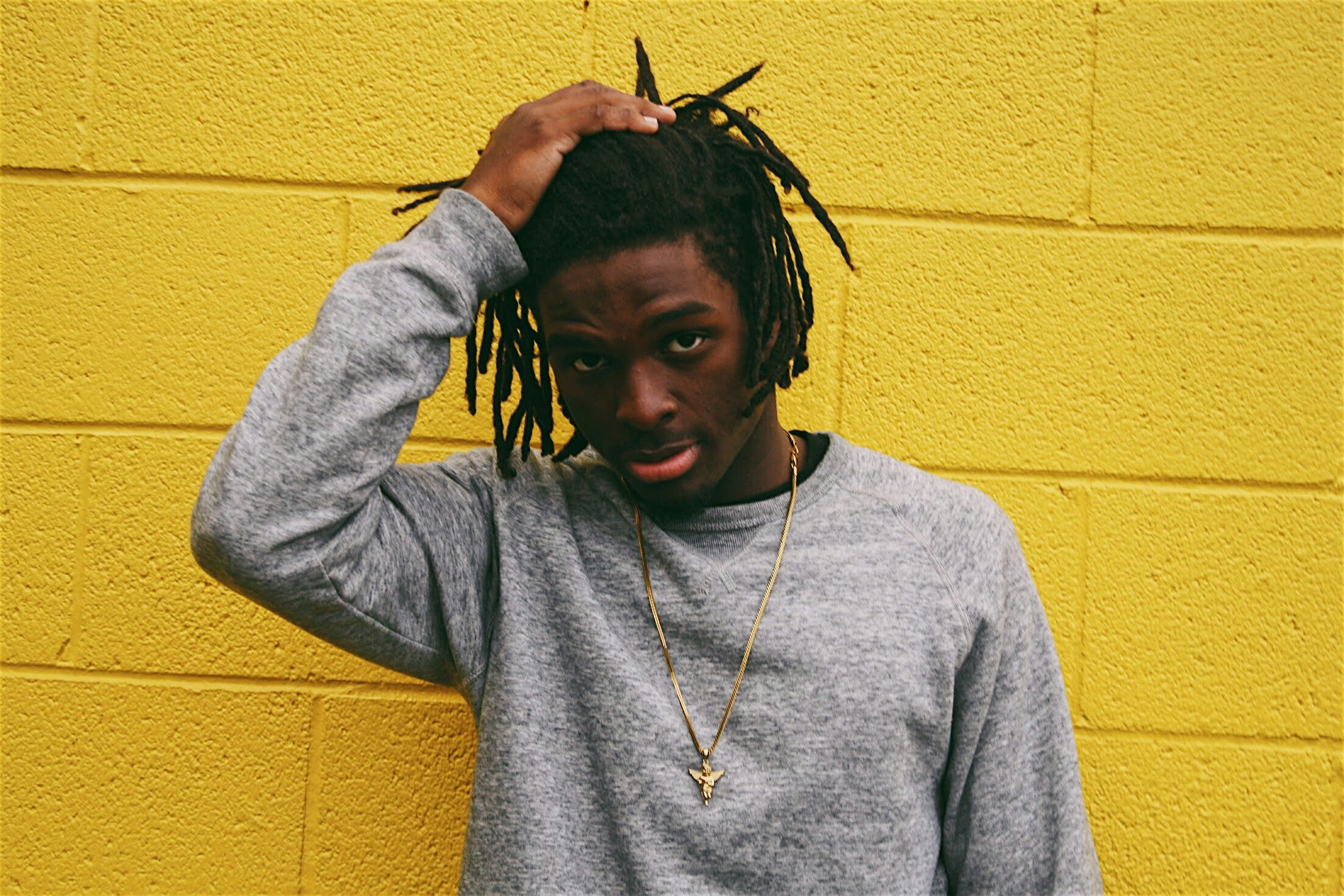 man wearing grey shirt and yellow background with hair clipped to the side