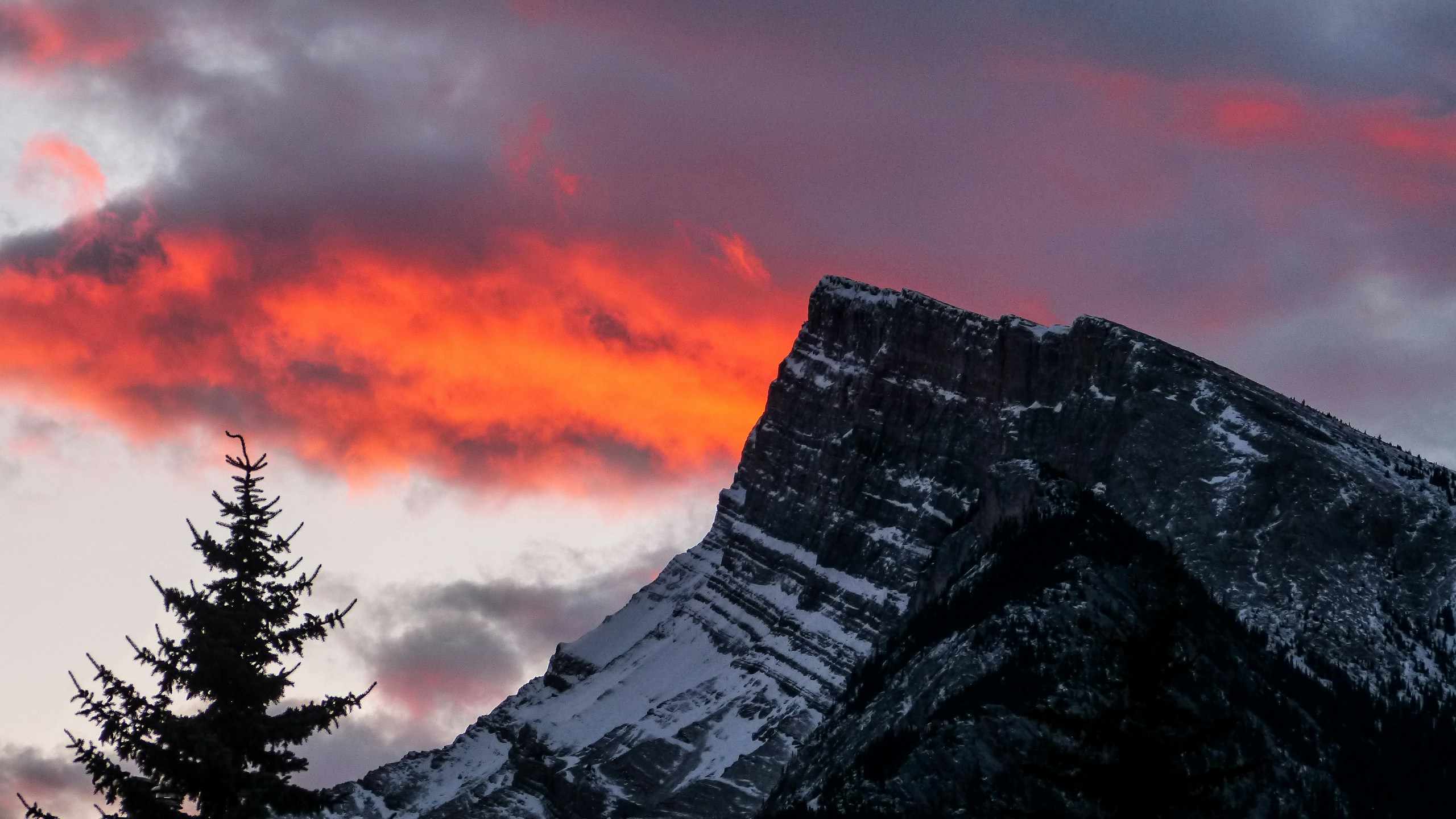 a mountain in the distance is silhouetted against a cloudy sky