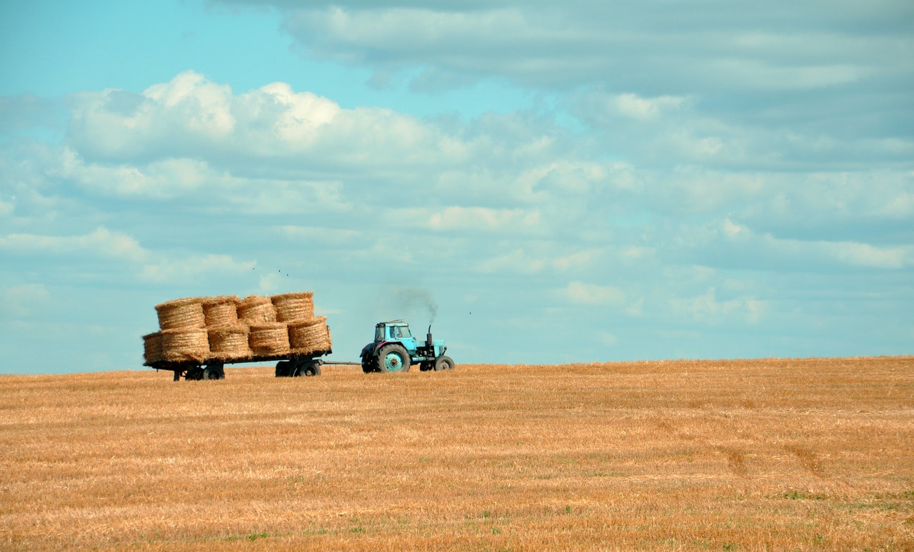 two large tractors hauling a bale of hay in a field