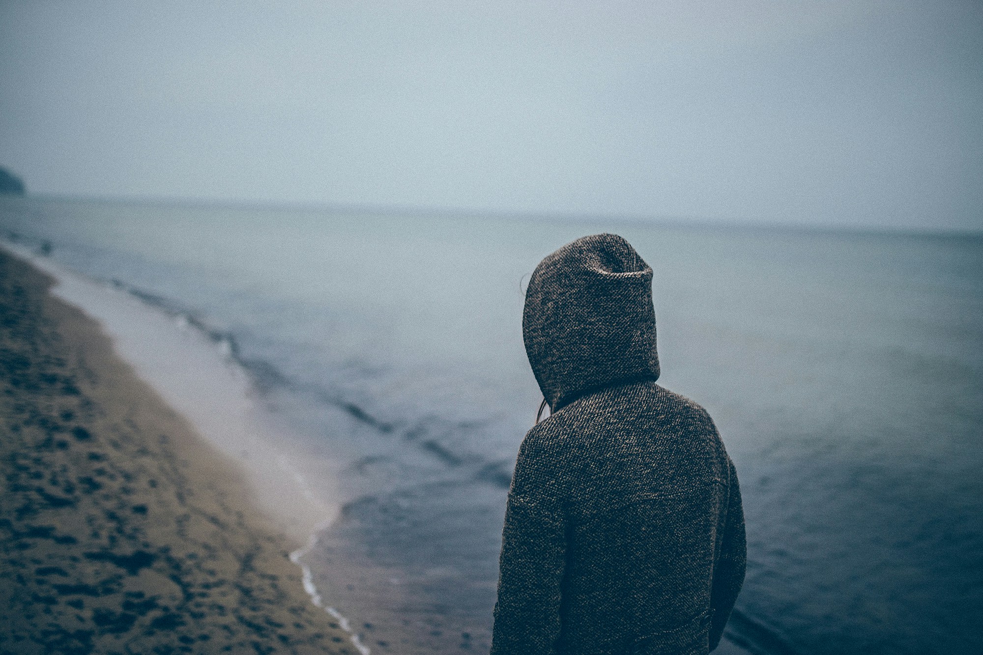 a person standing on a beach facing the ocean