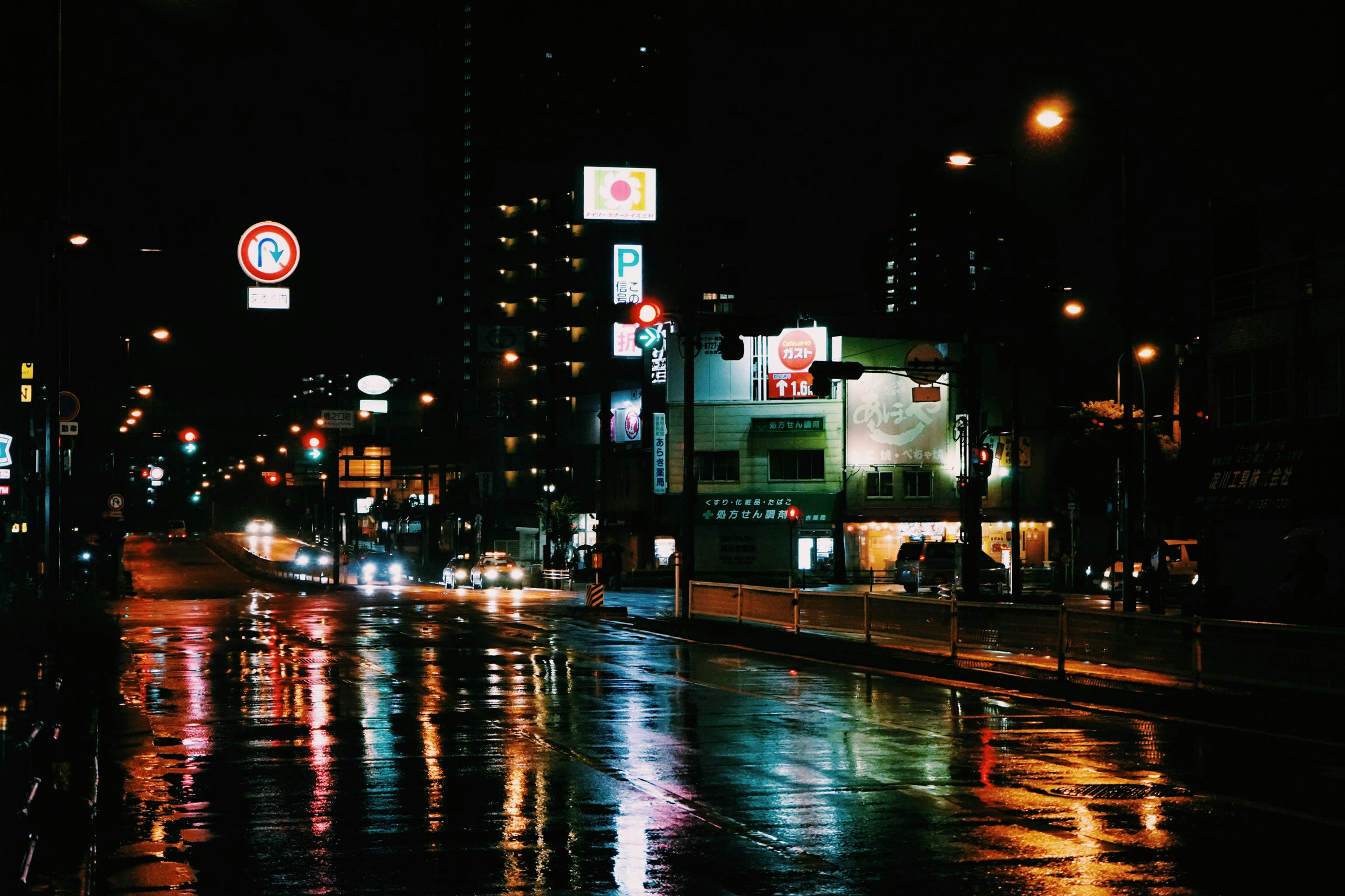 an empty wet city street is seen at night