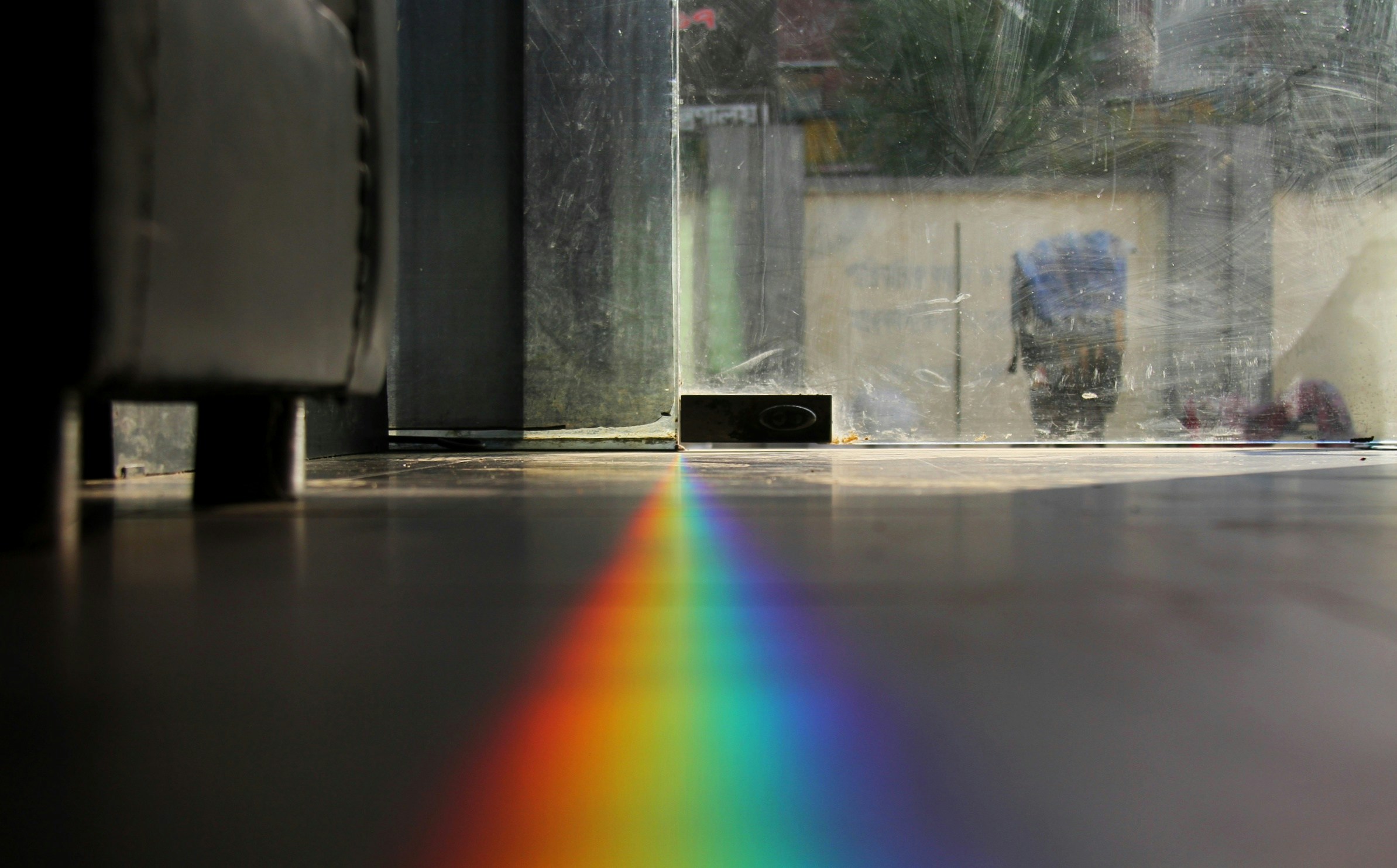 a rainbow being observed from the floor by a person with an umbrella