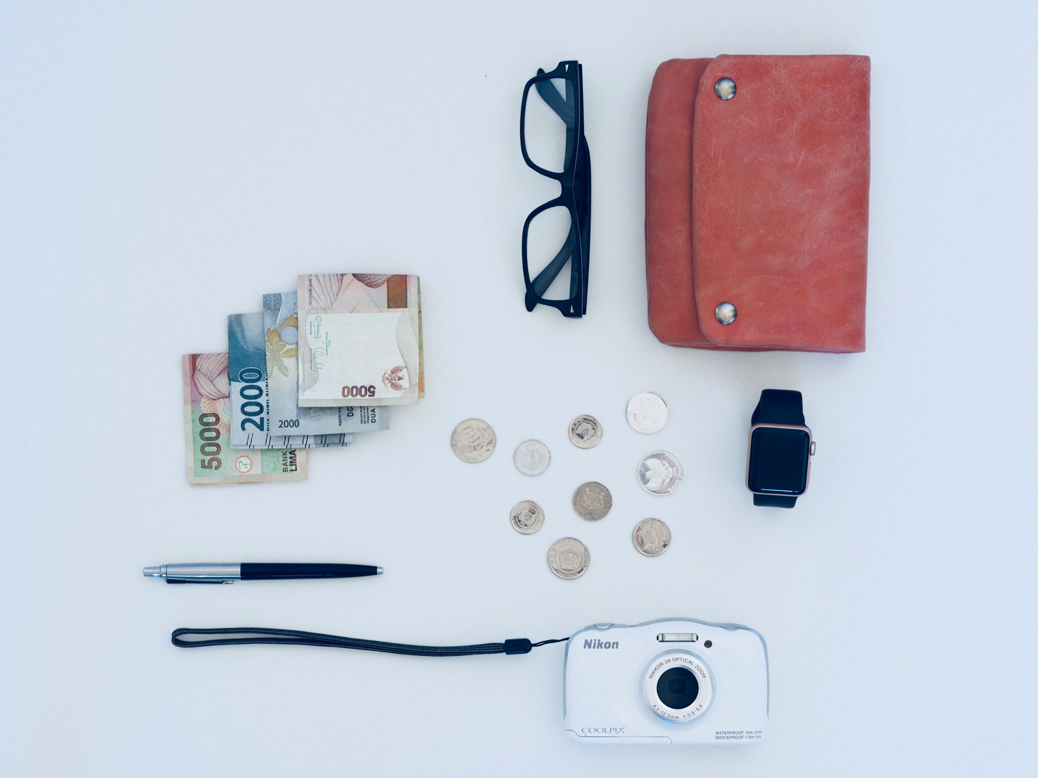 a wallet, glasses and pens laying beside a few other items
