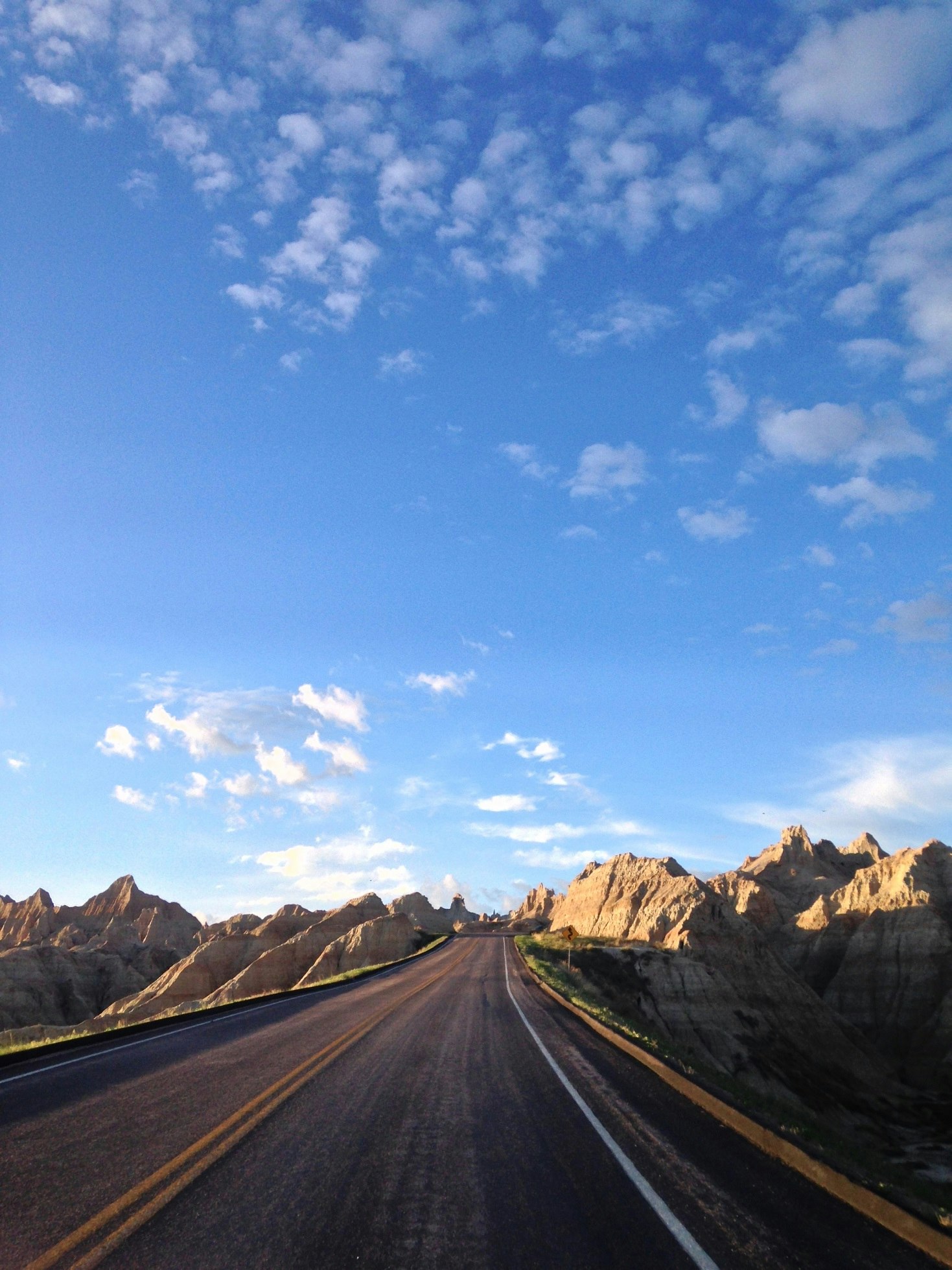 a road with mountains in the background and a blue sky