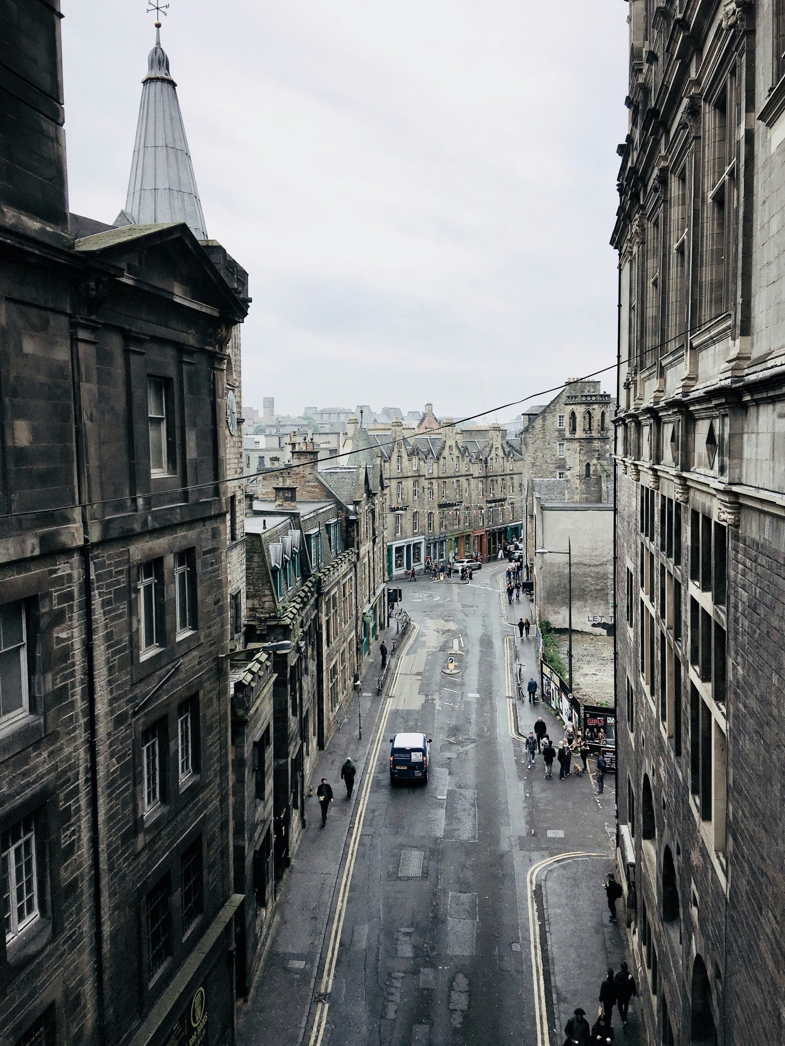 people and buildings lining a narrow street in the middle of an old city