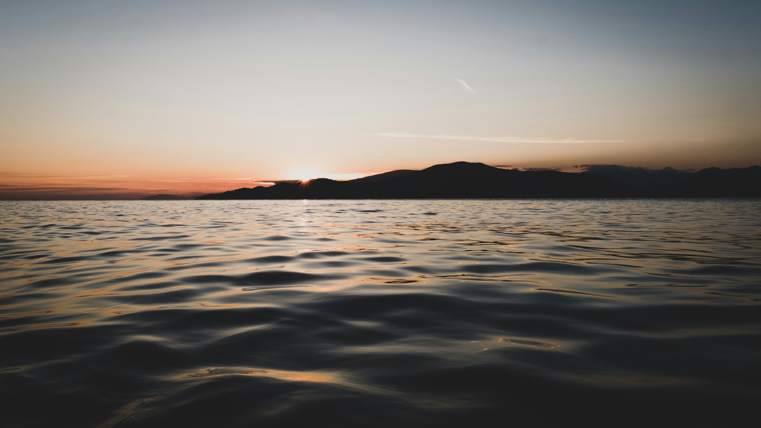 the sun is setting over water with ripples on the waves