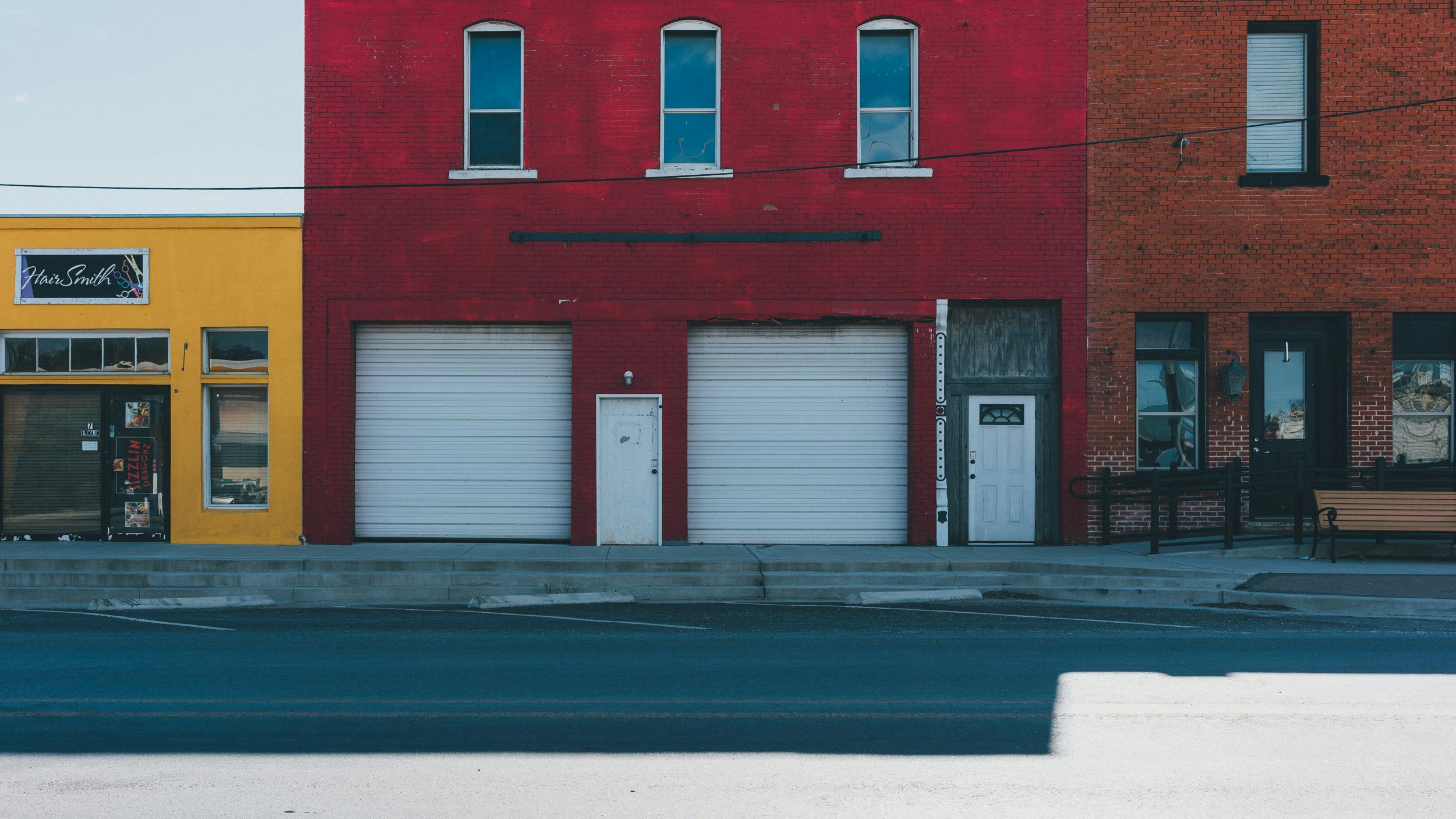 several garage doors and some benches on the side of the street