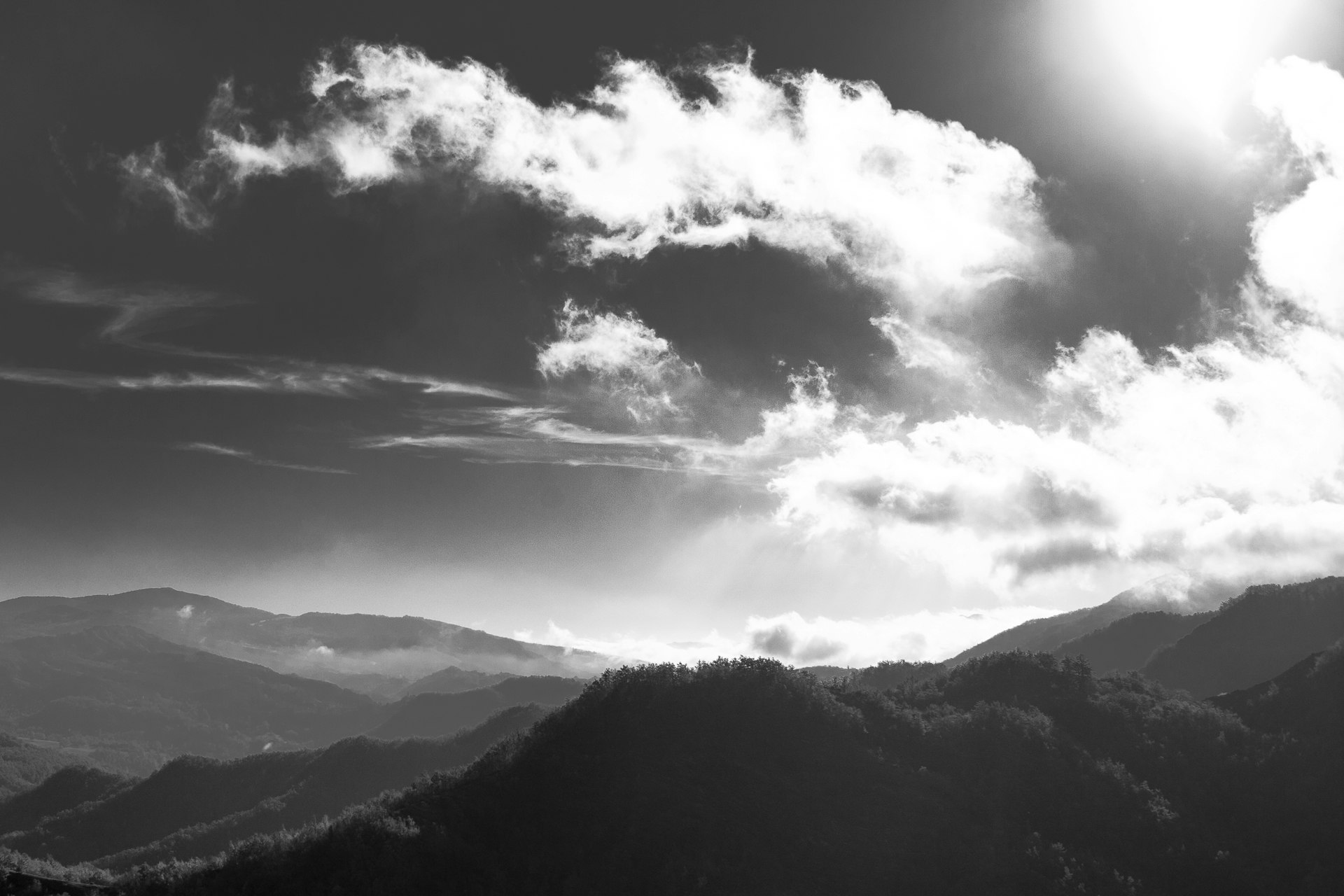 a black and white po of the sun shining over some mountains