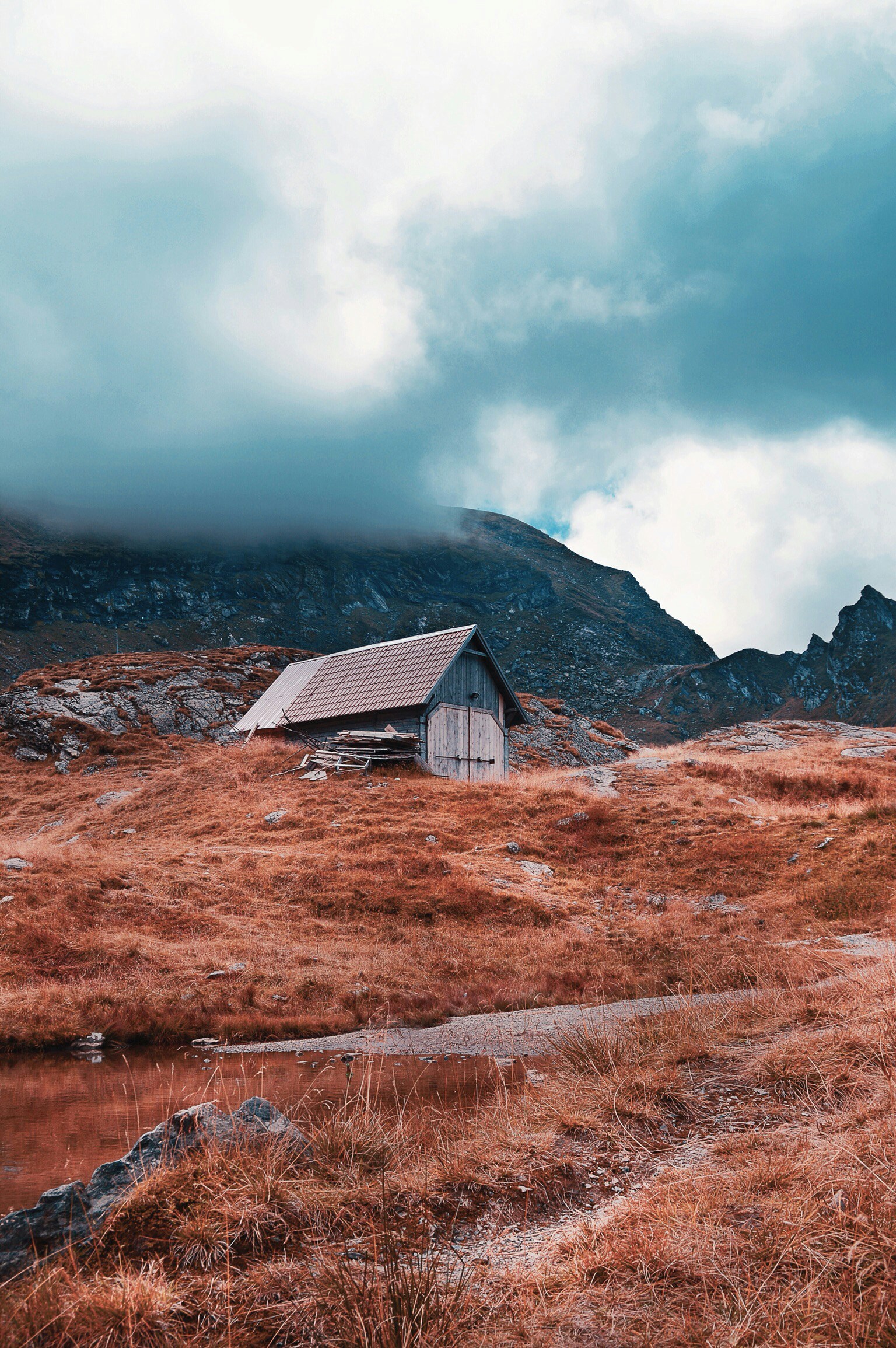 an old wooden house stands in an area with high mountain peaks