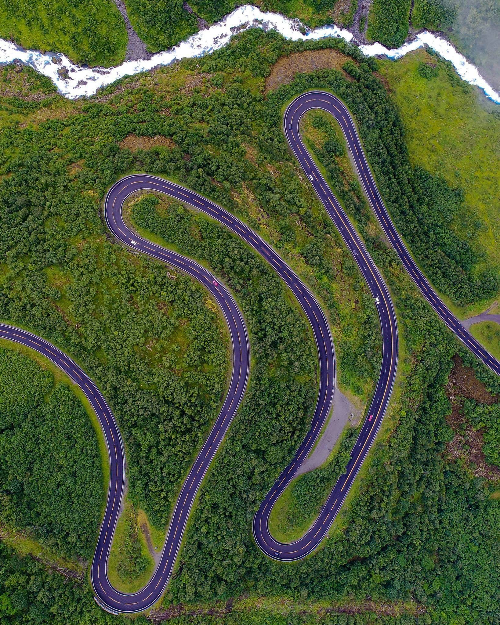 a scenic highway curves down a forested hillside